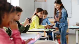 Schoolgirl,Shows,Her,Cellphone,To,Friends,,While,Other,Pupils,Engage