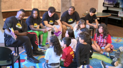 football players reading to kids at Malcolm X Library