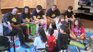 football players reading to kids at Malcolm X Library